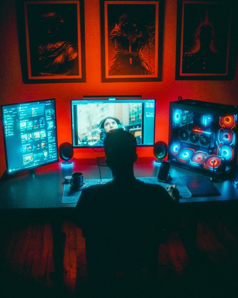 A gamer engrossed in a vibrant RGB computer setup with dual monitors at night.