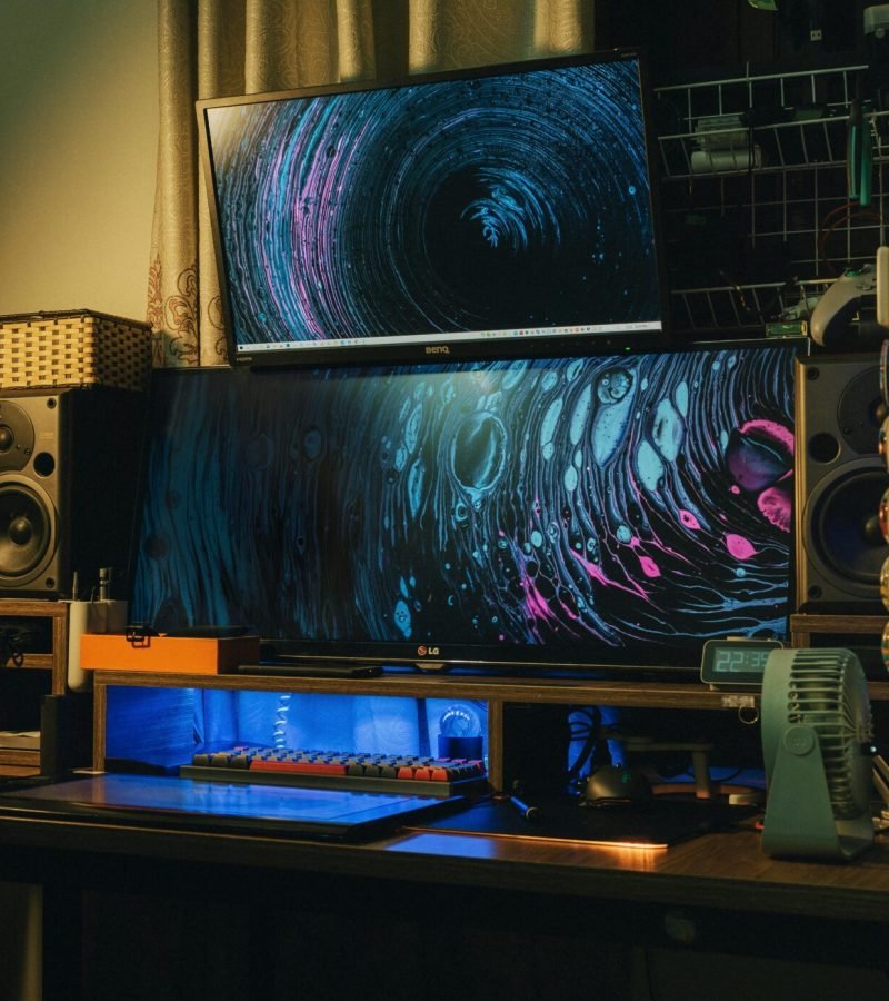 A cozy indoor modern computer setup with dual monitors and creative lighting.